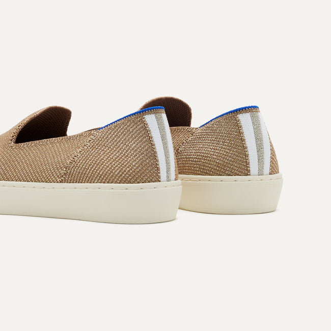 Close up of the heel of The Original Slip On Sneaker in Gold Twill, with Rothy's signature blue halo.