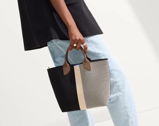 The image features a woman with a black and white tote bag, emphasizing a fashionable accessory choice.