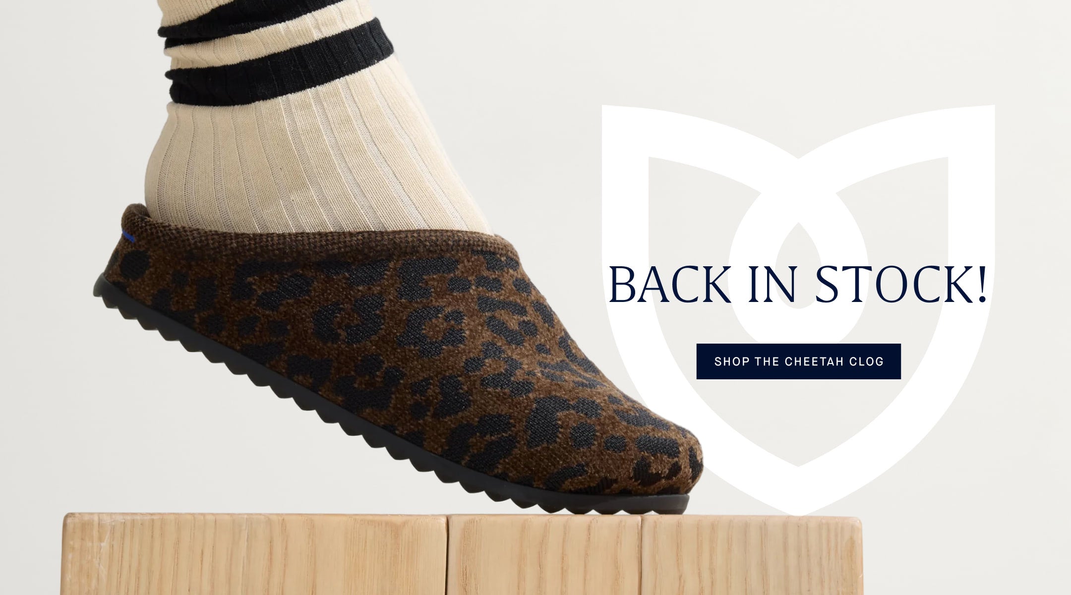 The Cheetah casual clog on a wooden block with 'Back in Stock' text and 'Shop The Cheetah clog."
