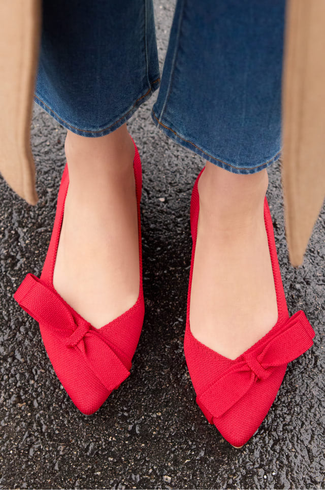 A pair of red flats featuring a bow detail, showcasing the Bow Point II design in a charming Cupid hue.