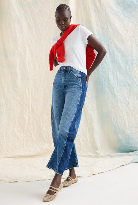 Woman wearing The Double Buckle Mary Jane in Dune Mesh, a white top, red cardigan, and blue jeans against a neutral background