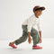 A child modeling The Kids Strap Sneaker in Watermelon. 