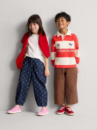 Two children wearing The Kids Stretch Sneaker in Firecracker, and The Kids Stretch Sneaker in Bubble Pop.