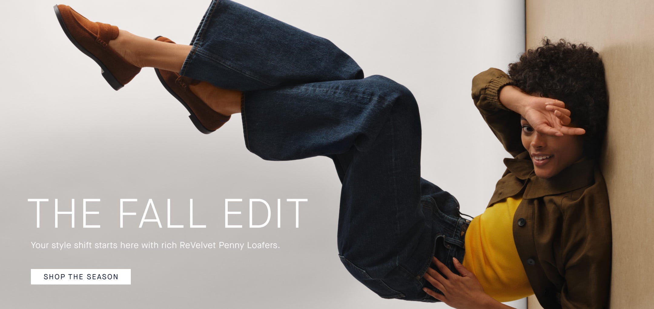 A person lying on their back wearing The Penny Loafer in Russet The image features promotional text overlay reading 'THE FALL EDIT' and 'SHOP THE SEASON' on a light gray background.