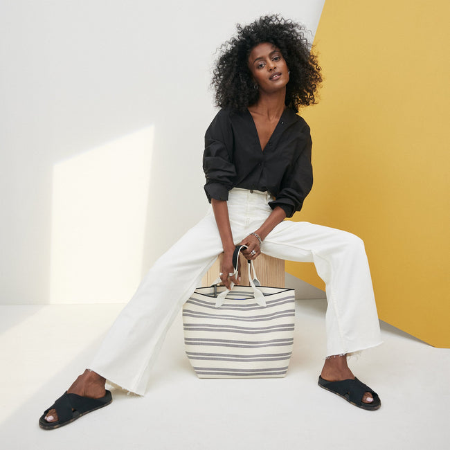 An alternative view of a model holding The Lightweight Tote in Polar Stripe.
