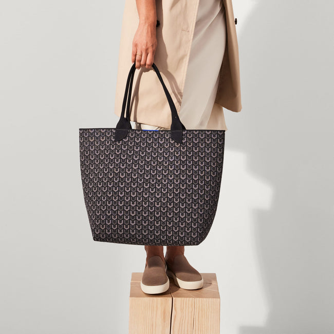 Model holding The Lightweight Tote in Signature Black.