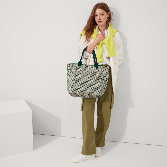 An alternate view of model holding The Lightweight Tote in Signature Green.