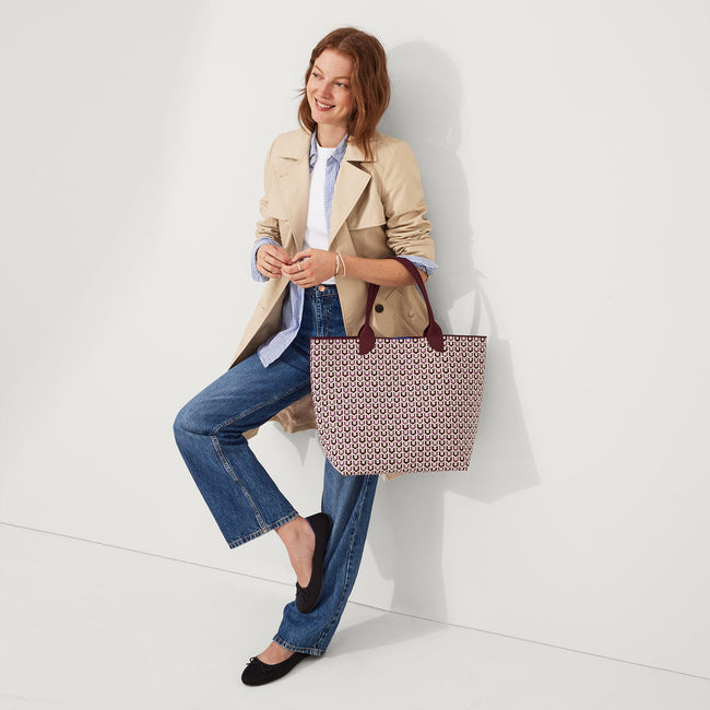 An alternate view of model holding The Lightweight Tote in Signature Plum.