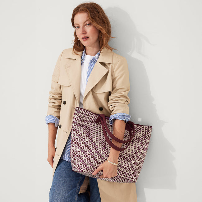 Model holding The Lightweight Tote in Signature Plum.