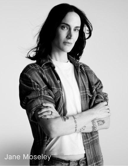 Black and white portrait of Jane Moseley with arms crossed, wearing a plaid button-up shirt over a white T-shirt, on a light gray background with the text 'Jane Moseley' at the bottom left.
