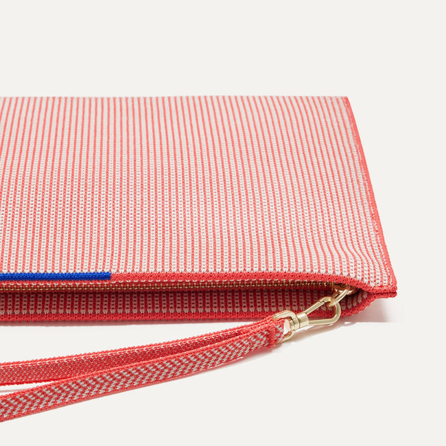 Close up of the zipper closure and wrist strap of The Wristlet in Coral Grid.
