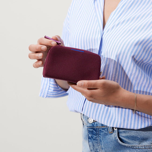 The Mini Universal Pouch in Collegiate Currant held by model.