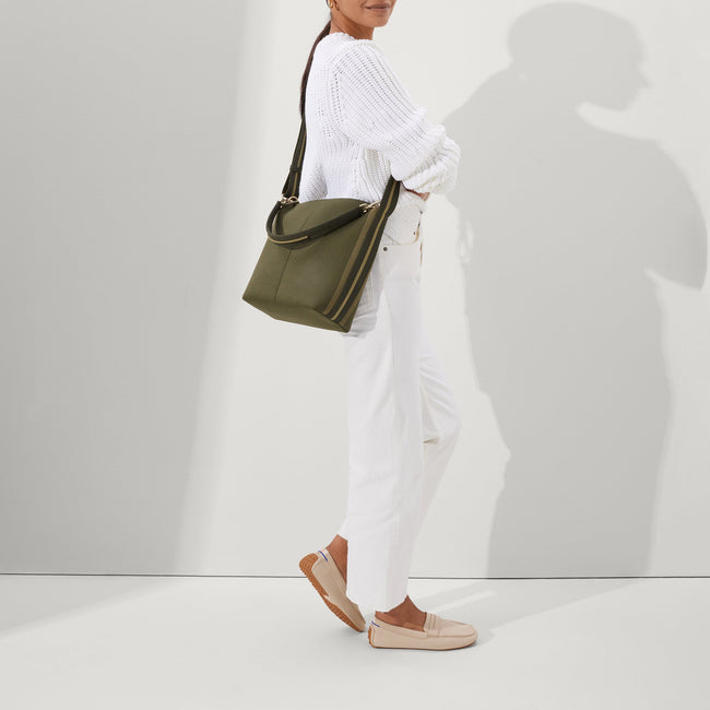 The Mini Zip Bucket in Cypress worn as a crossbody by a female model, shown in motion from the right.