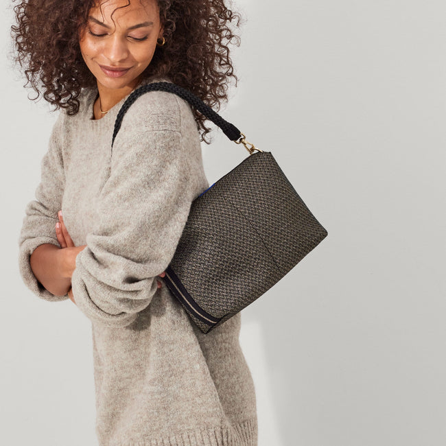 The Daily Crossbody in Sparkle Herringbone,, carried over the shoulder of a female model, shown from the left.