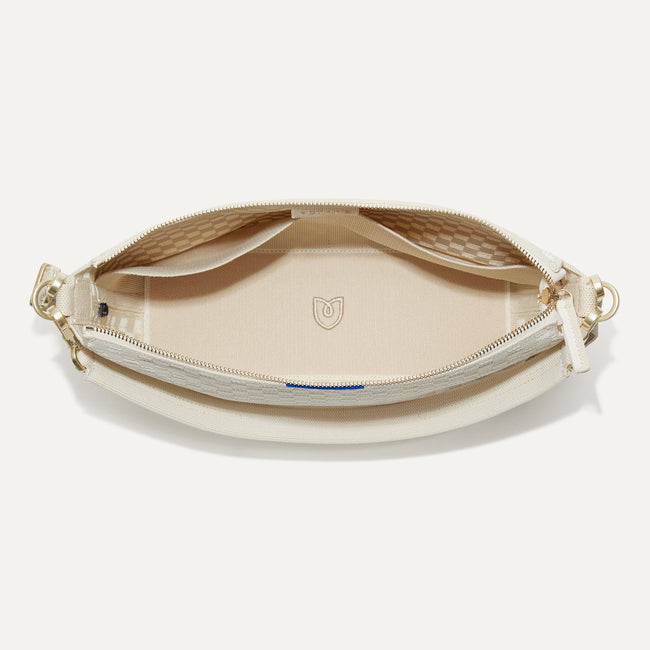 The Daily Crossbody Bag in White Sand shown from the top down, with zipper open and interior exposed.