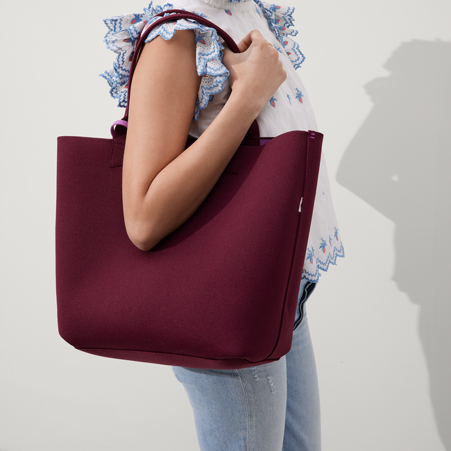 Model holding The Reversible Lightweight Tote in Collegiate Currant.
