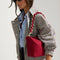 The Shoulder Strap in Cranberry Chain, shown paired with The Daily Crossbody, worn by a model and shown from the side. 