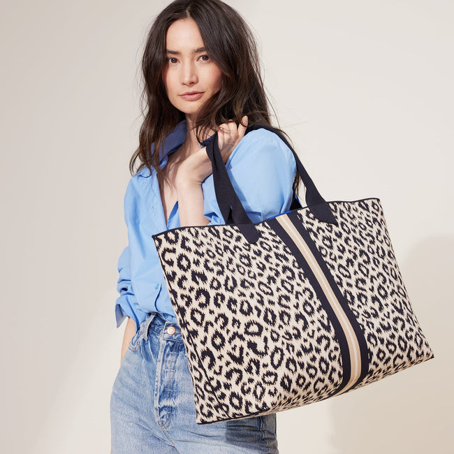 The Lightweight Mega Tote in Sandy Cat, carried by its top handles by a model, shown from the front.