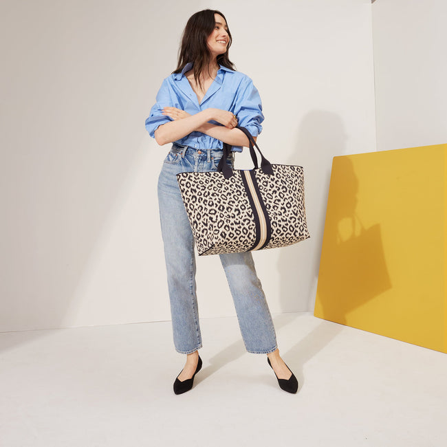 The Lightweight Mega Tote in Sandy Cat, carried by its top handles by a model, shown from the front, with the reverse side showing.