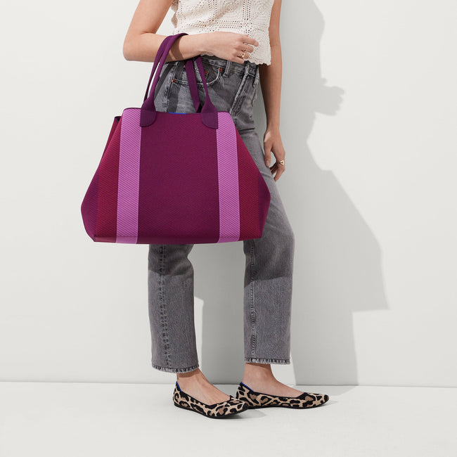 The Lightweight Mega Tote in Mulberry Rugby Stripe, carried by its top handles by a model, shown from the front. 