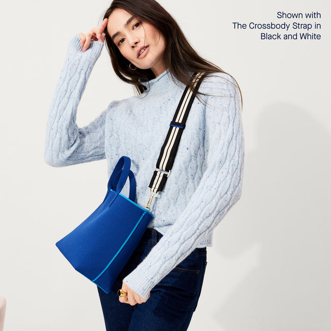 The Lightweight Petite Tote in French Blue, worn as a crossbody by a model, shown from the side with the Crossbody Strap in Black and White Stripe.