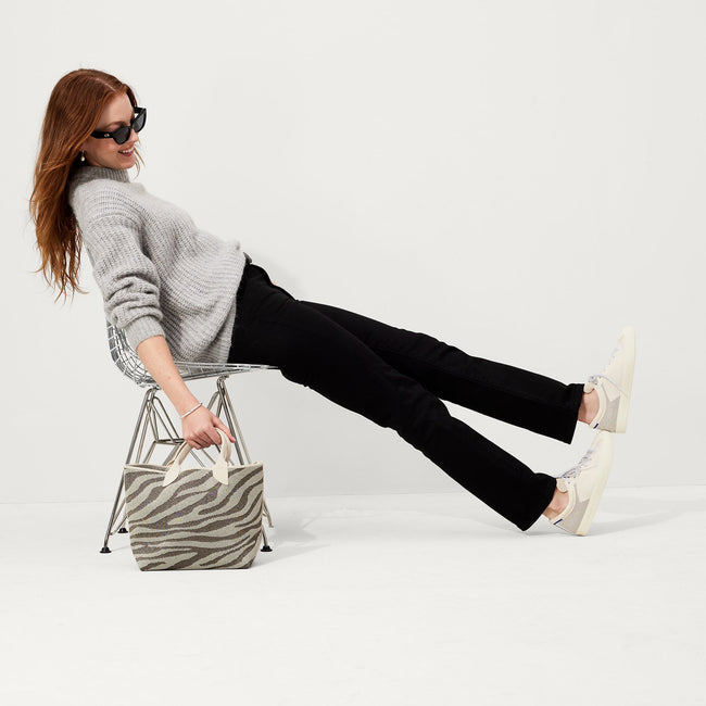 The Lightweight Petite Tote in Shimmer Zebra, carried by its top handles by a model, shown from front.