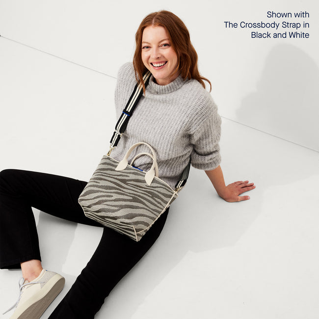 The Lightweight Petite Tote in Shimmer Zebra, worn as a crossbody by a model, shown from the front with the Crossbody Strap in Black and White Stripe.