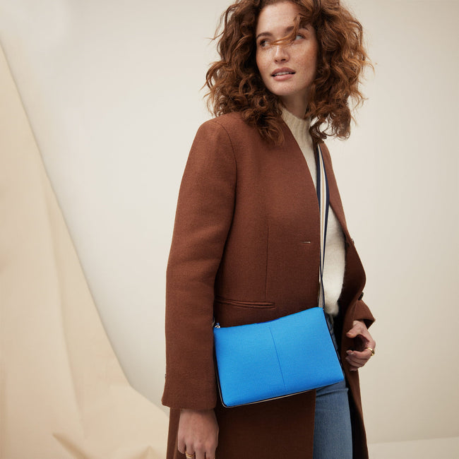 The Casual Crossbody in Cerulean Sky, worn as a crossbody by a model, shown from the side. 