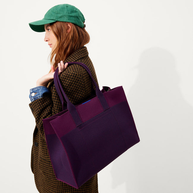 The Classic Tote in Dark Aubergine, worn over the shoulder by a model, shown from the side.