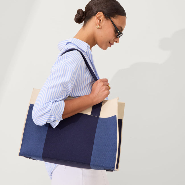 The Classic Tote in Luxe Blue, worn over the shoulder by a model, shown from the side.