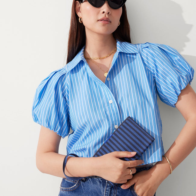 The Wallet Wristlet in Navy Stripe, held by a model at an angle, shown from the front.