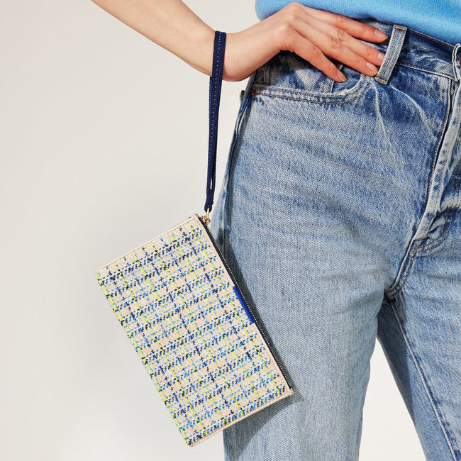 The Wallet Wristlet in Spring Tweed, held by a model by the wrist strap.
