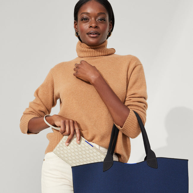 The Wallet Wristlet in Vanilla Basketweave, shown packed into The Lightweight Tote by a model.