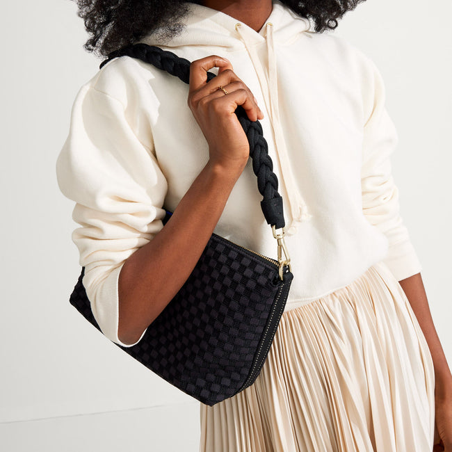 The Braided Shoulder Strap in Black, shown paired with The Daily Crossbody, worn by a model and shown from the side. 