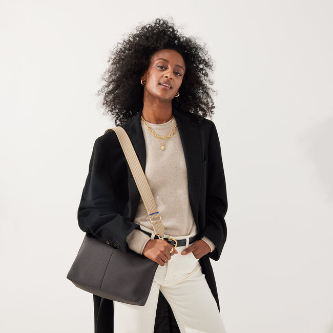 The Crossbody Strap in Brown Sugar, shown paired with The Daily Crossbody, worn by a model, shown from the front.
