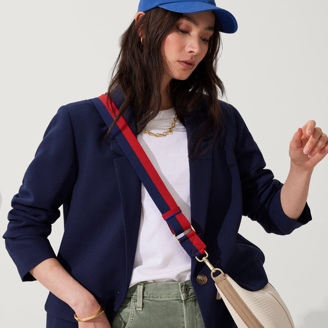 The Crossbody Strap in Navy & Red, shown paired with The Crescent Bag, worn by a model, shown from the side