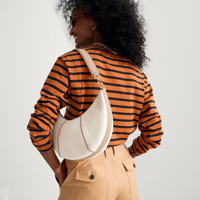 Model holding The Crescent Bag in Celestine by the shoulder strap, shown from the front.