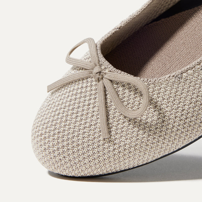 Close up of the rounded toe and bow detail of The Ballet Flat in Platinum Metallic.