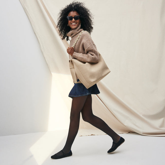 The Shoulder Strap in White, shown paired with The Bucket Bag, worn by a model and shown from the side.