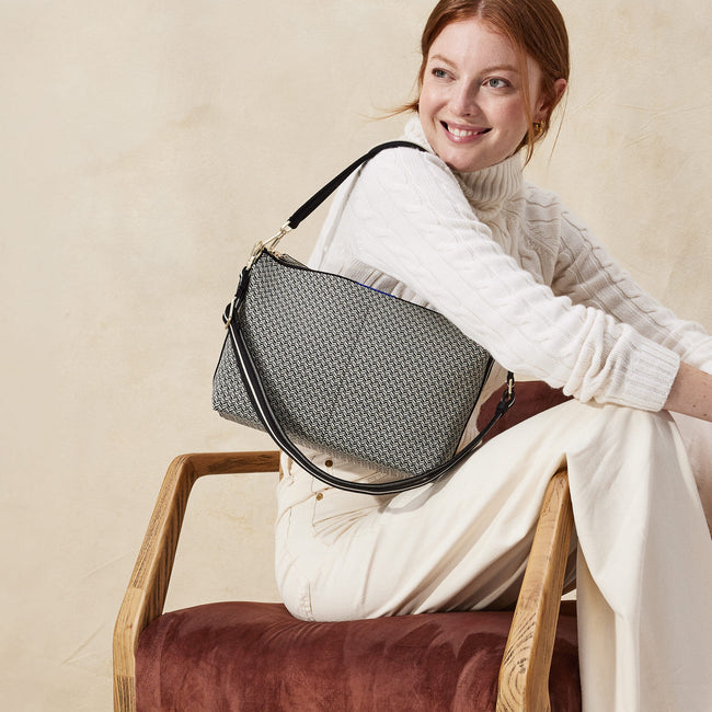 The Daily Crossbody in Black Mist Herringbone, carried over the shoulder of a female model, shown from the right.