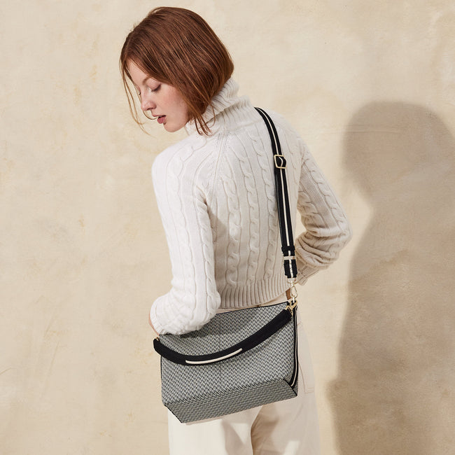The Daily Crossbody in Black Mist Herringbone, worn as a crossbody by a female model, shown from the back.