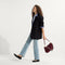 model | Overlay:: Shown with The Shoulder Strap (sold separately). | Alt:: At alternate image of a model carrying The Daily Crossbody in ReVelvet™ Syrah.