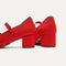 Close up of the heel of The Double Buckle Mary Jane Heel in Bright Red, with Rothy's signature blue halo.
