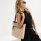 Alternate view of a model carrying The Two-Way Tote in Sandbar showing the ivory striped side.