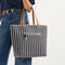 Alternate view of a model carrying The Two-Way Tote in Shadow showing the indigo striped side.