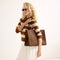 Alternate image of The Classic Tote in Cinnamon Open Knit, carried by its top handles by a model, shown from the front.