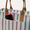 A closeup of The Classic Tote in Watermelon Market Stripe, focusing on the exterior zip pocket. 