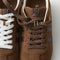 Overlay:: Extra pair of laces included—swap for a new look anytime. | Alt:: Close up of the top of The Ivy Sneaker in ReVelvet Cinnamon, showing different lace choices.