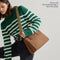 The Classic Handbag in Sierra Brown being carried by a model shown paired with The Crossbody Strap in Neon Pine Stripe.
