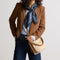 hover | The Daily Crossbody in Macadamia Open-Knit, carried over the shoulder of a female model, shown from the right.